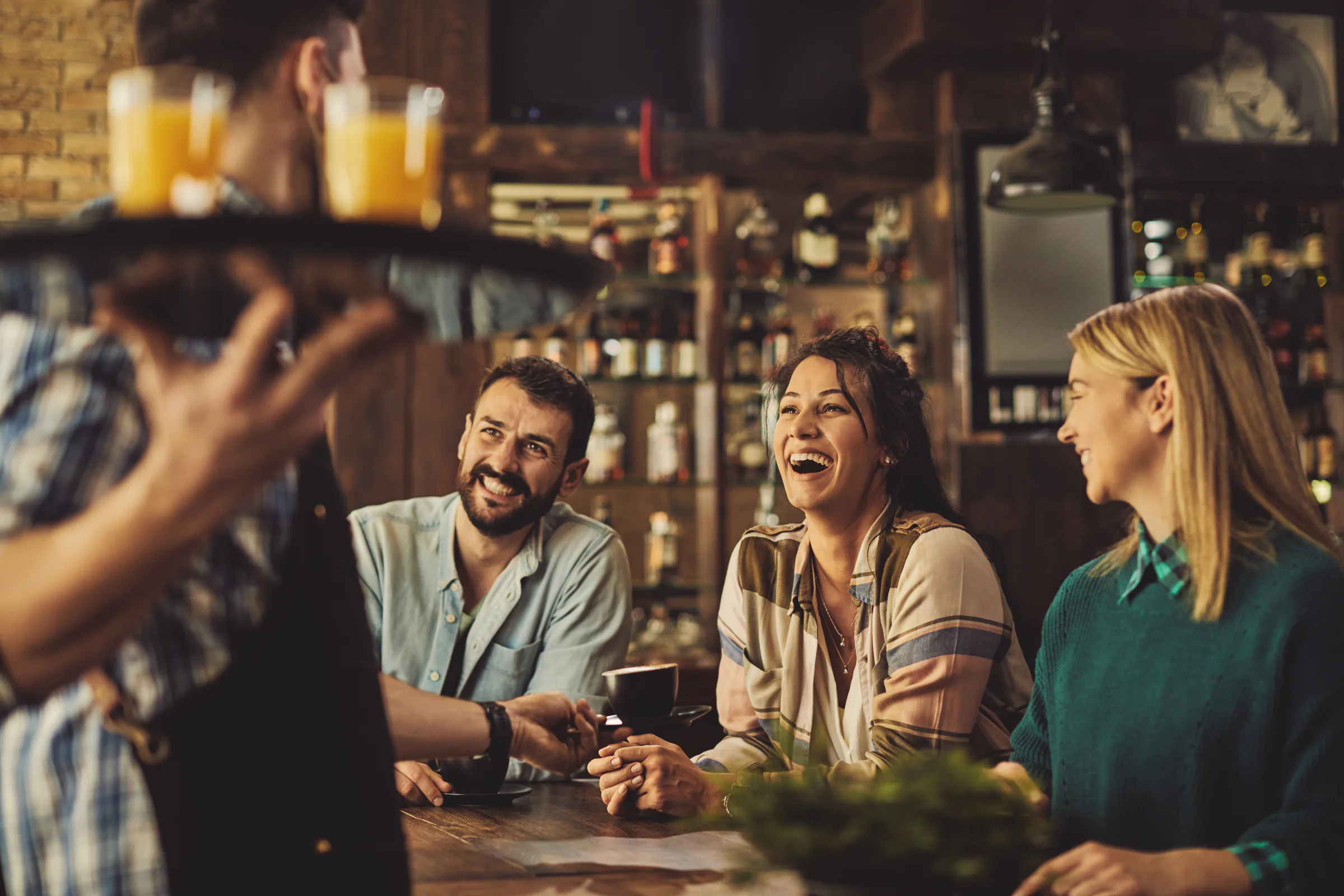 Grupo de amigos conversando con un camarero en una cafetería