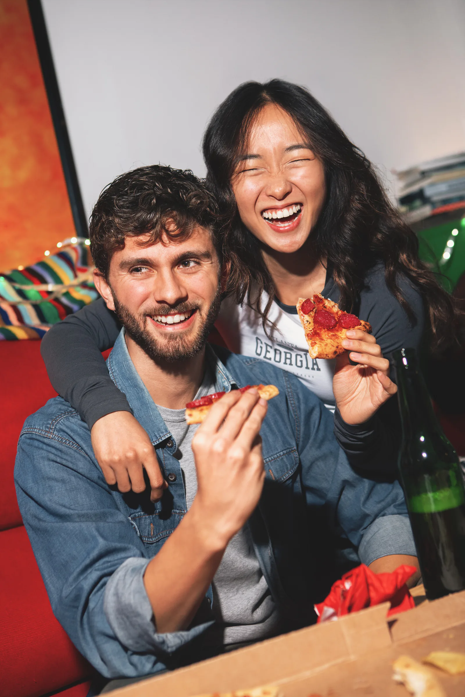 Pareja de amigos riendo mientras come pizza en un restaurante