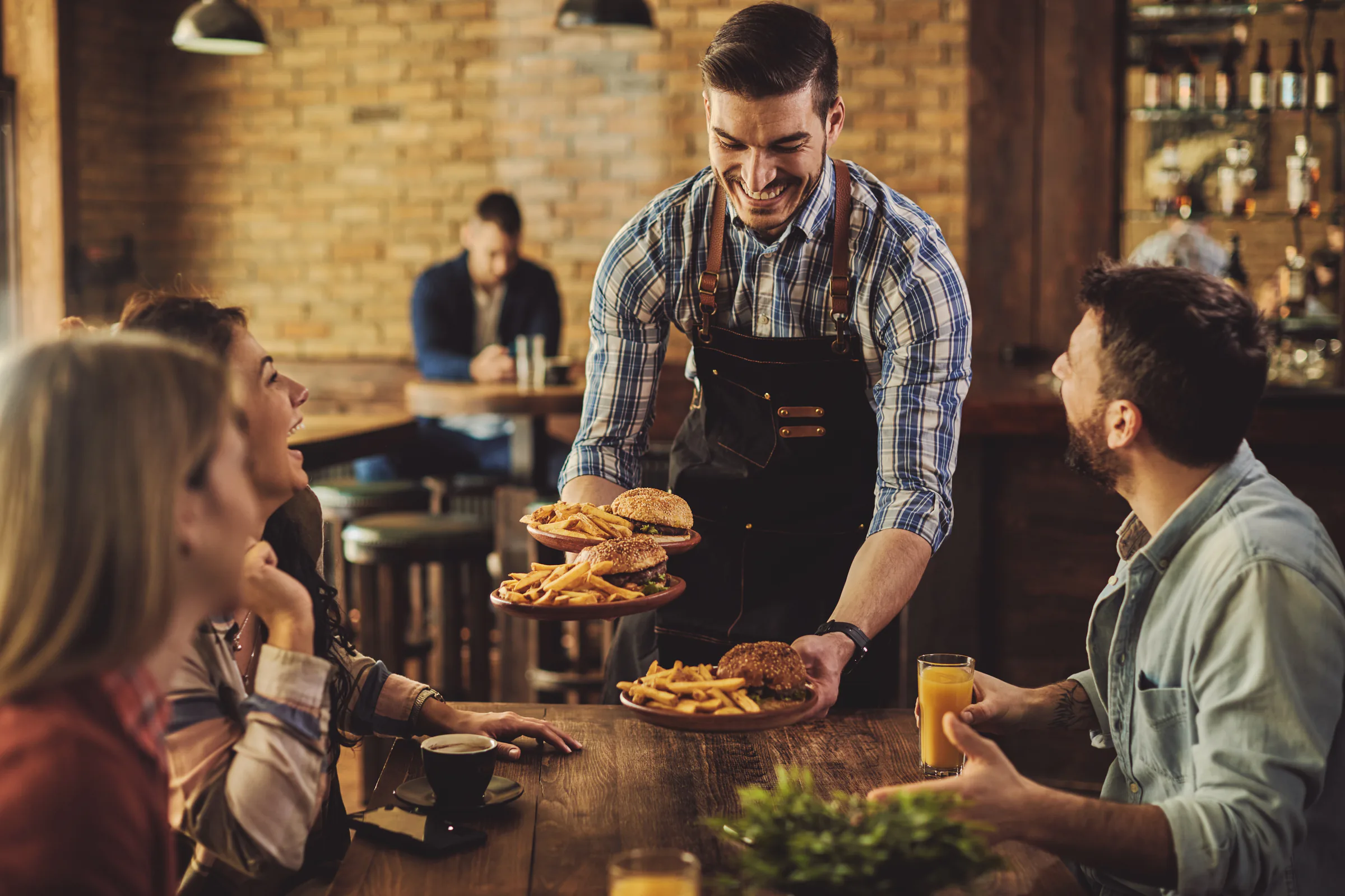 Camarero sirviendo hamburguesas a un grupo de clientes