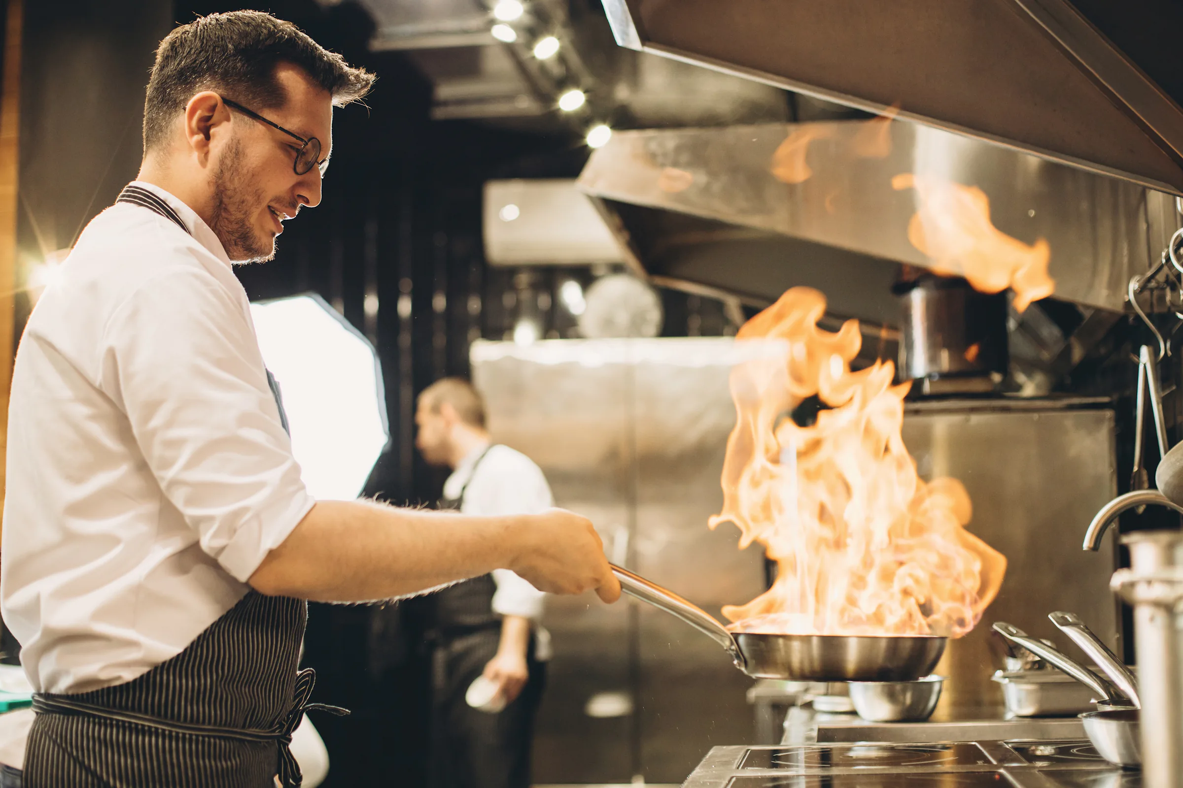 Chef cocinando a la llama en una cocina profesional