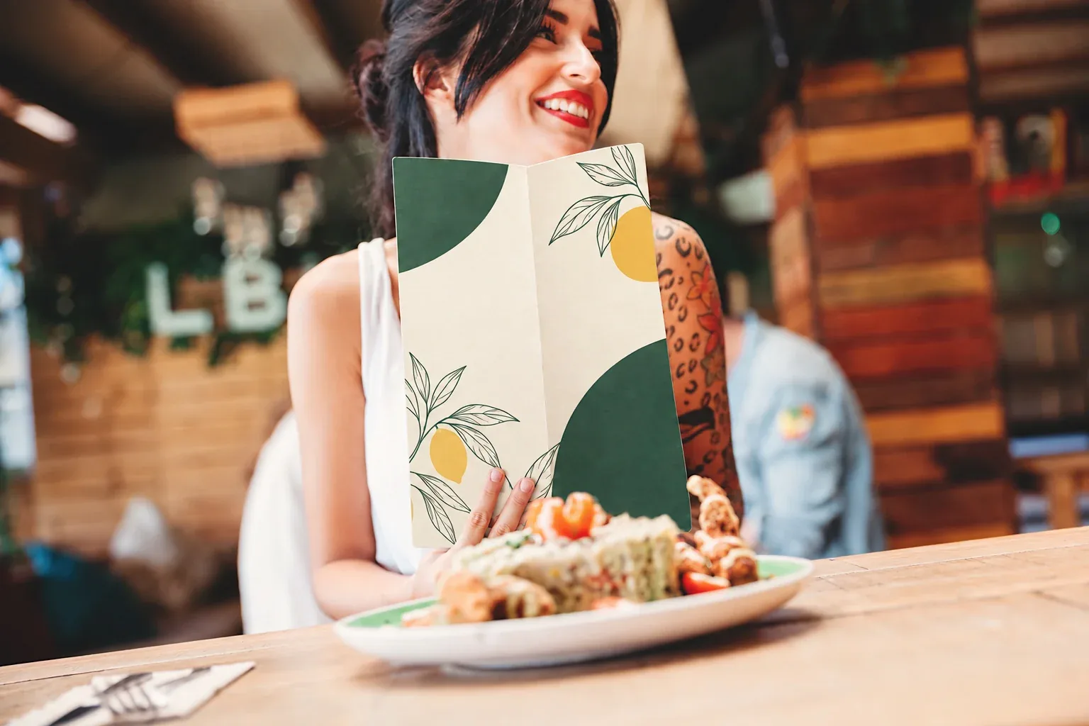 Clienta sonriente con la carta del restaurante delante de un plato