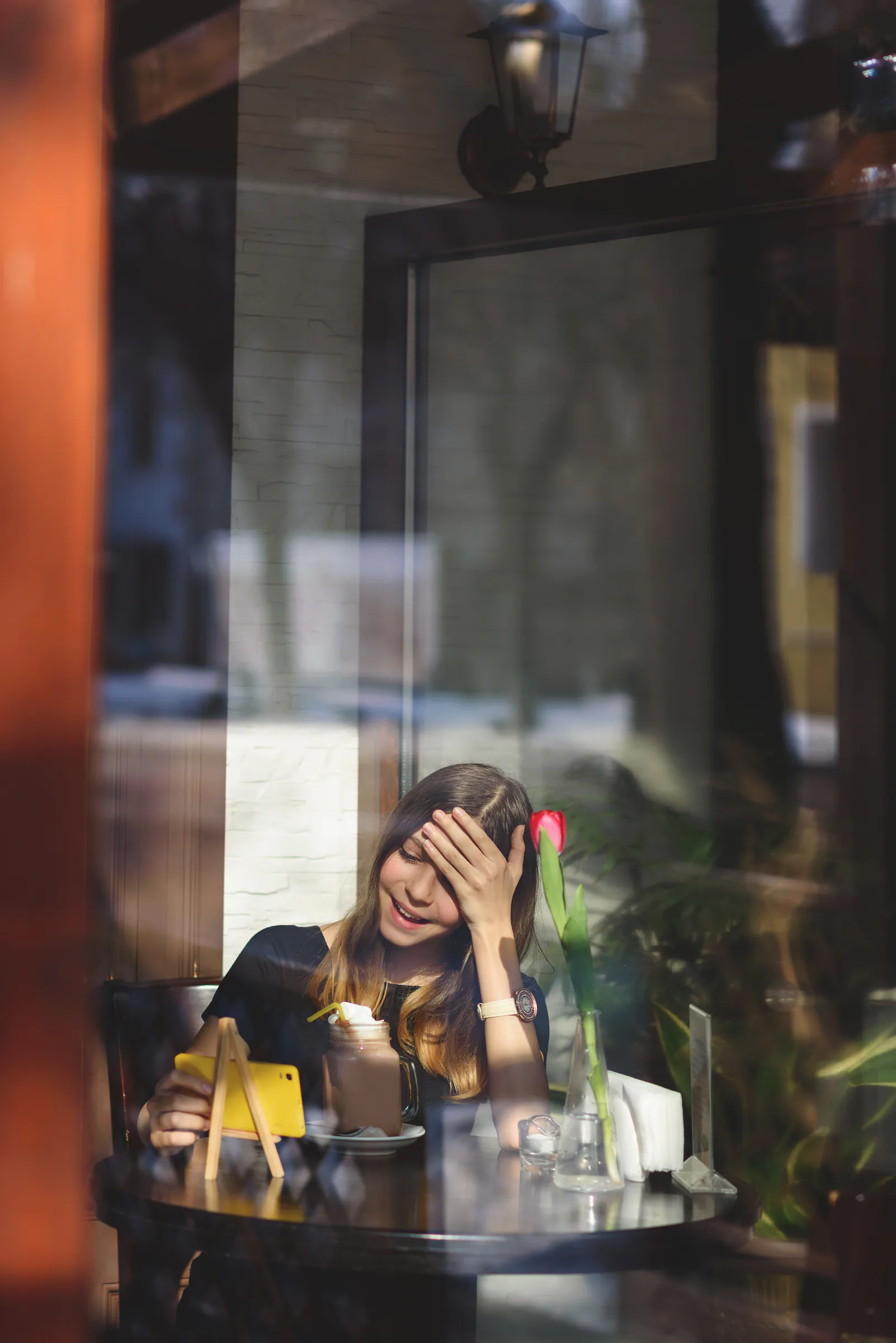 Clienta mirando el móvil mientras toma una bebida en una cafetería