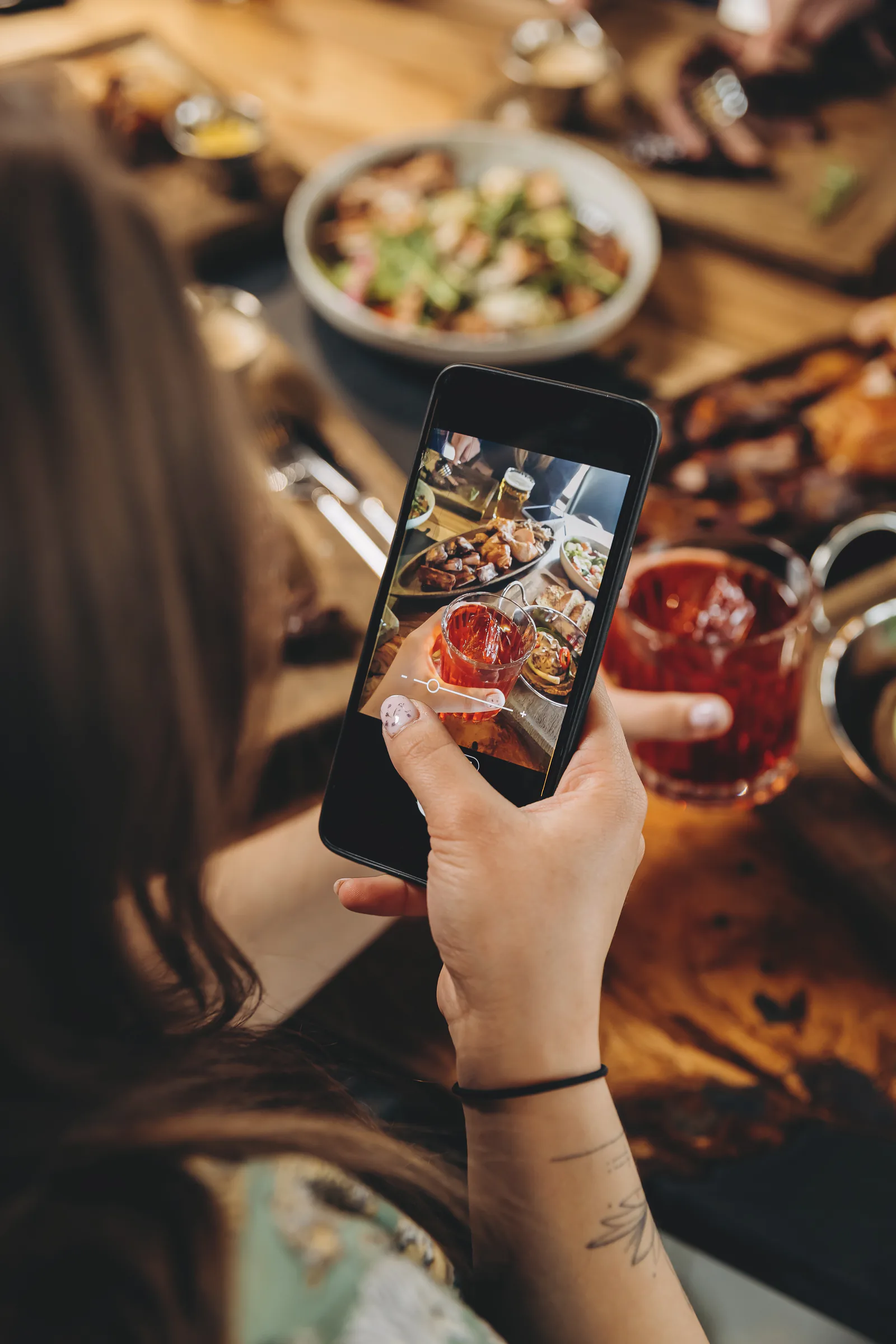 Clienta fotografiando con el móvil una mesa con comida y bebidas