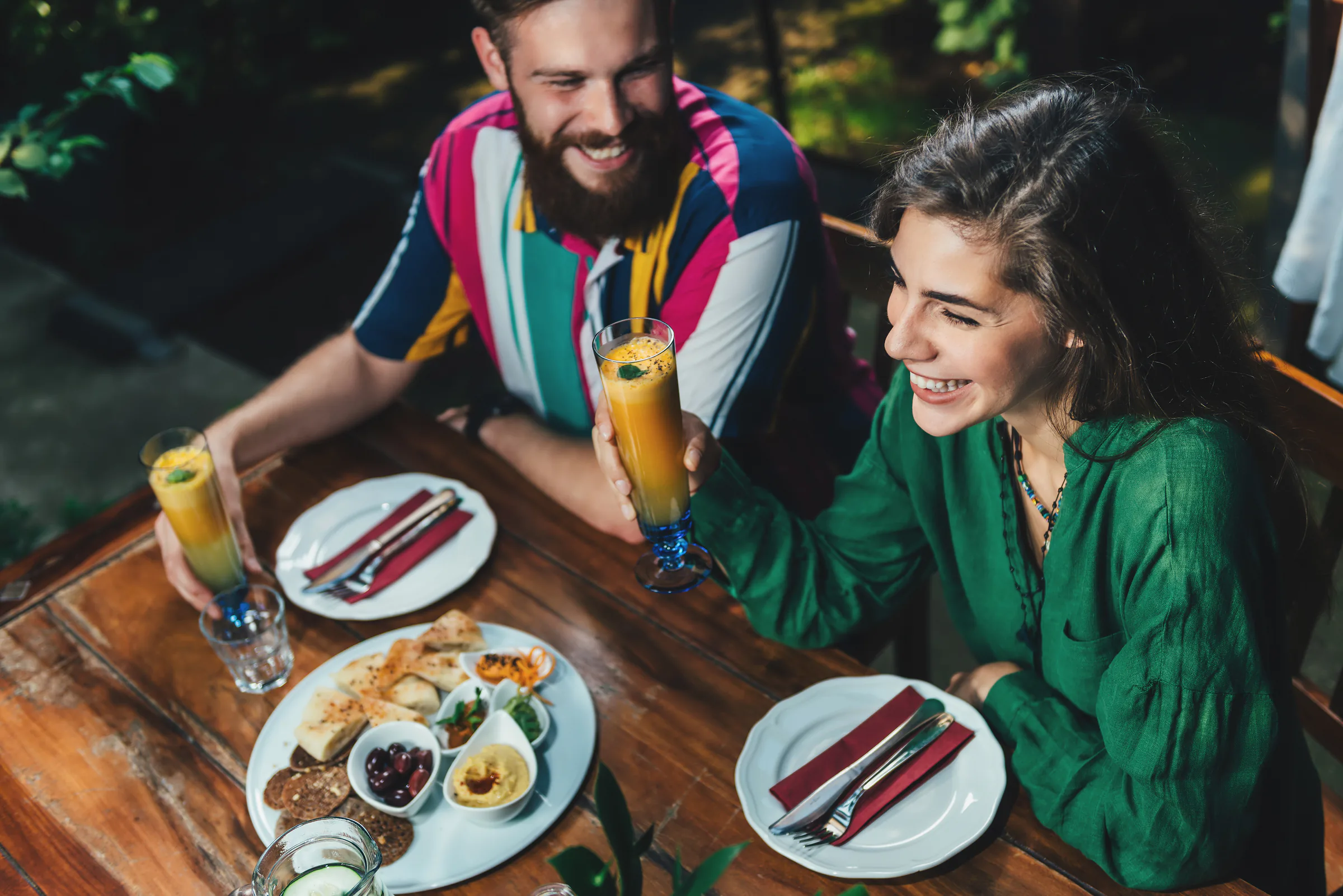 Pareja sonriente compartiendo una cena vegetariana y bebidas